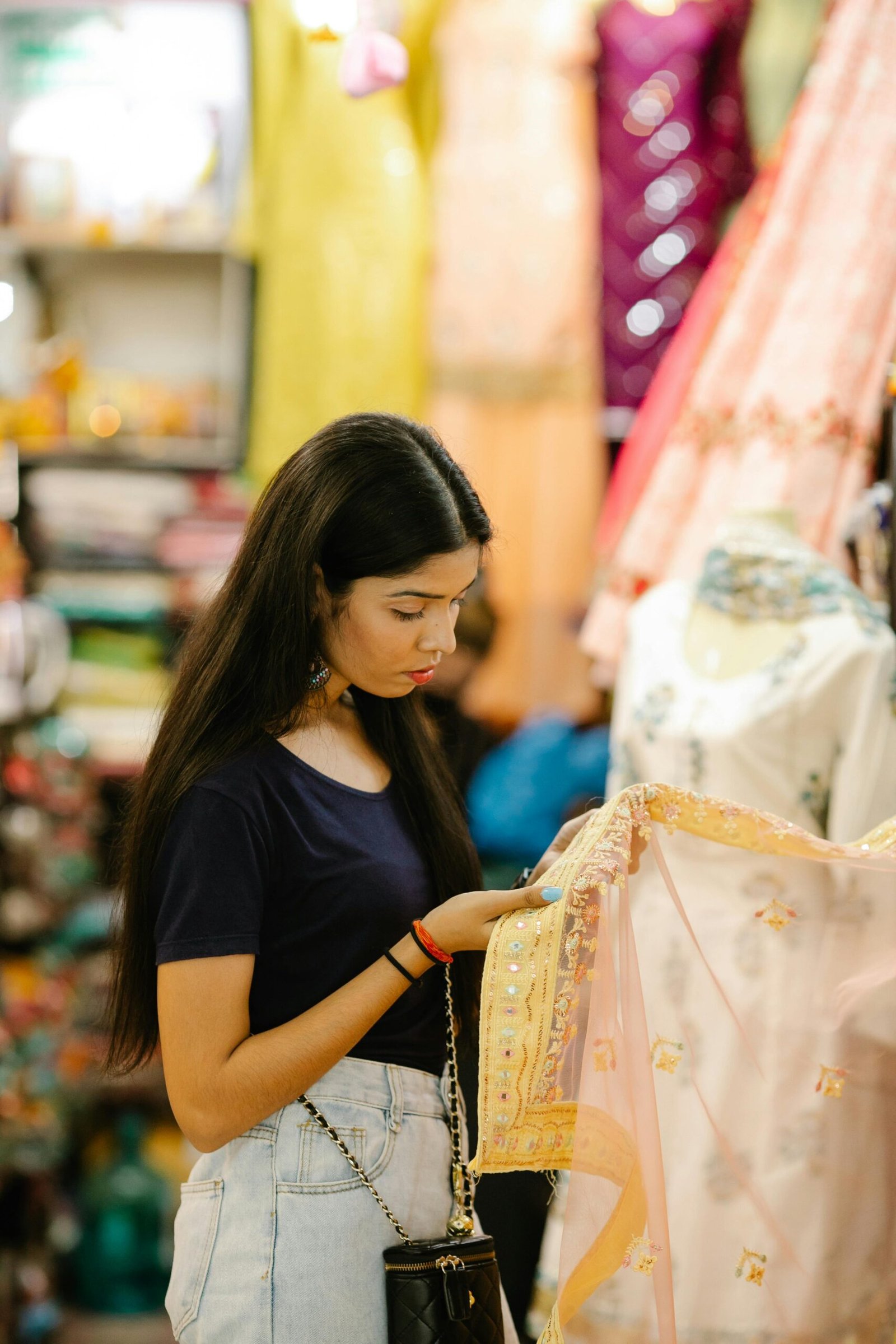 A young woman explores colorful textiles in a bustling fabric market, showcasing Indian culture and fashion.