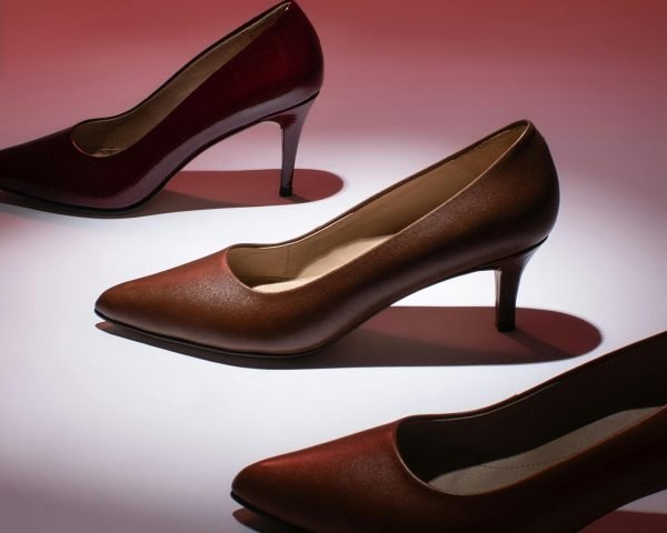 Stylish high heel shoes showcased on a vibrant red gradient for a fashion shoot.